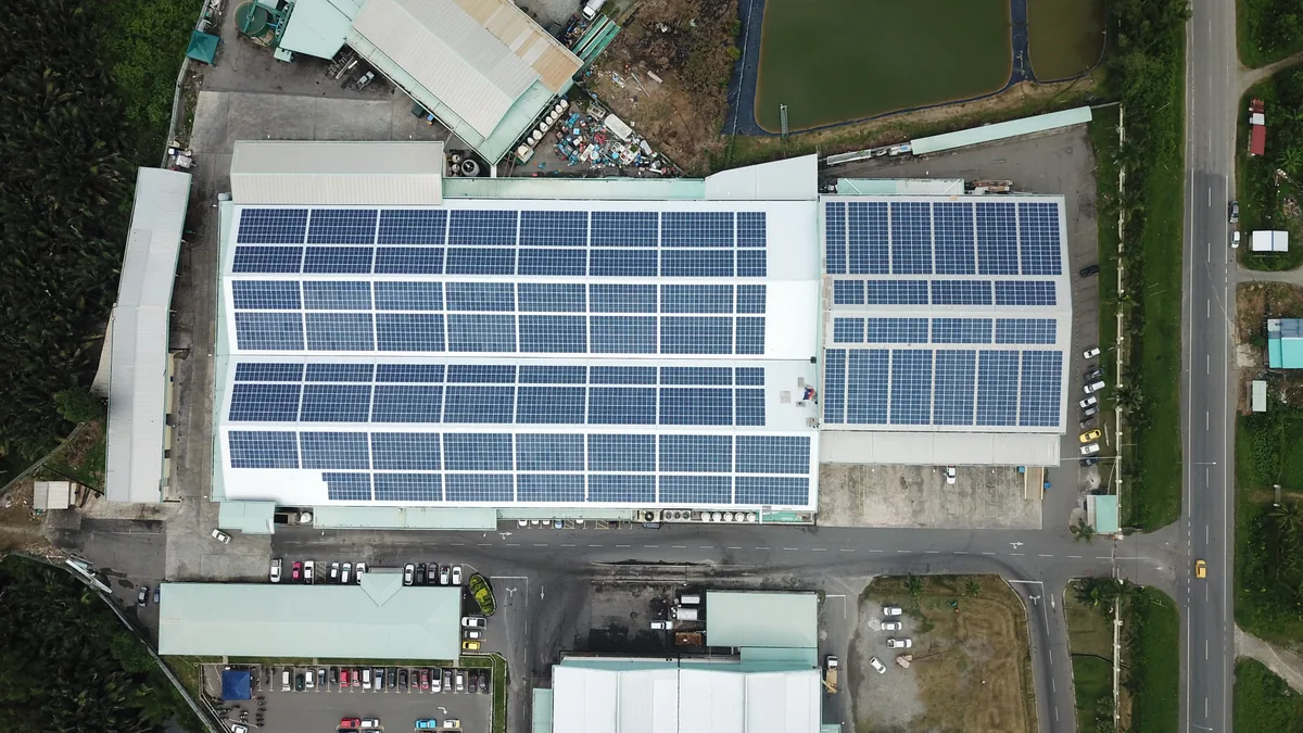 Aerial view of large rooftop solar installation on a food manufacturing factory in coastal Tuaran, Sabah