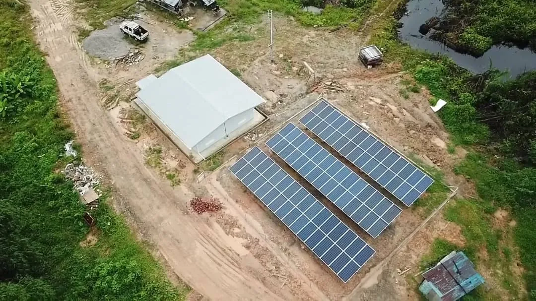 Solar panel array in a rural village clearing surrounded by tropical forest in Sarawak